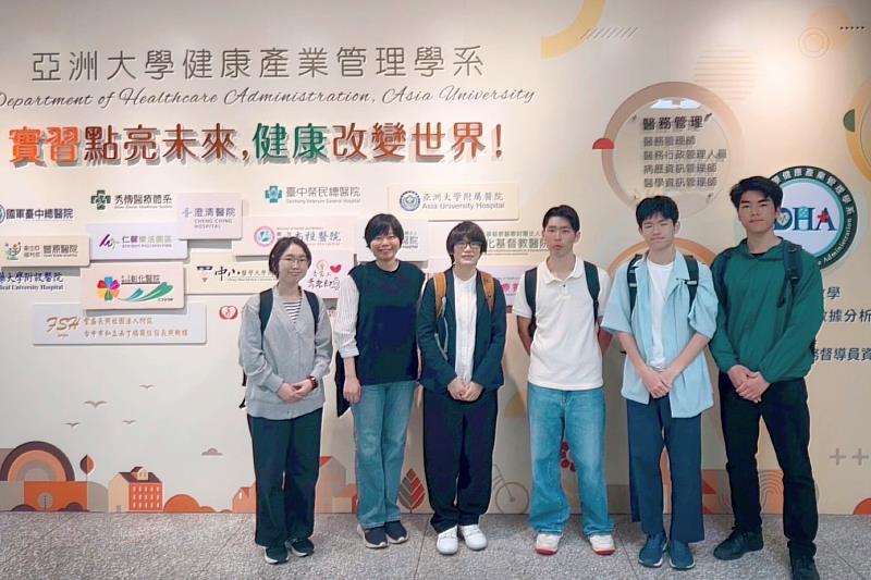 神戶大學師生與亞大健管系林冠含副教授（左2）於學系看板前大合照。林副教授與身旁的大一學生（左1）愉快互動，神戶大學余玟欣助理教授（左3）亦一同見證兩校師生的專業交流。