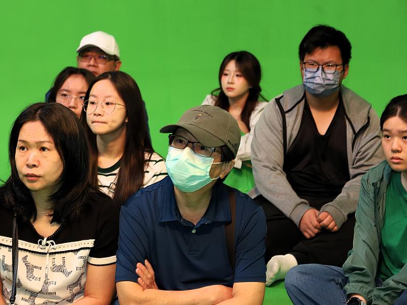 考生與家長戴著口罩，專注聽取資傳系AI綠幕攝影棚解說。