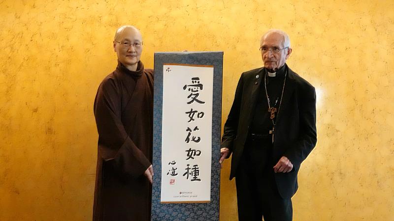 世界宗教博物館發展基金會執行長顯月法師(左)致贈創辦人心道法師所書的「愛如花如種」卷軸給天主教斯卡拉布里尼修會樞機主教托瑪士。(圖由世界宗教博物館提供)