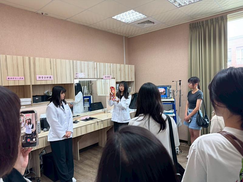 在嗓音吞嚥實驗室中，學姊手持精細的解剖喉部模型，解碼語言治療的核心專業，考生也以手機記錄專業場景。