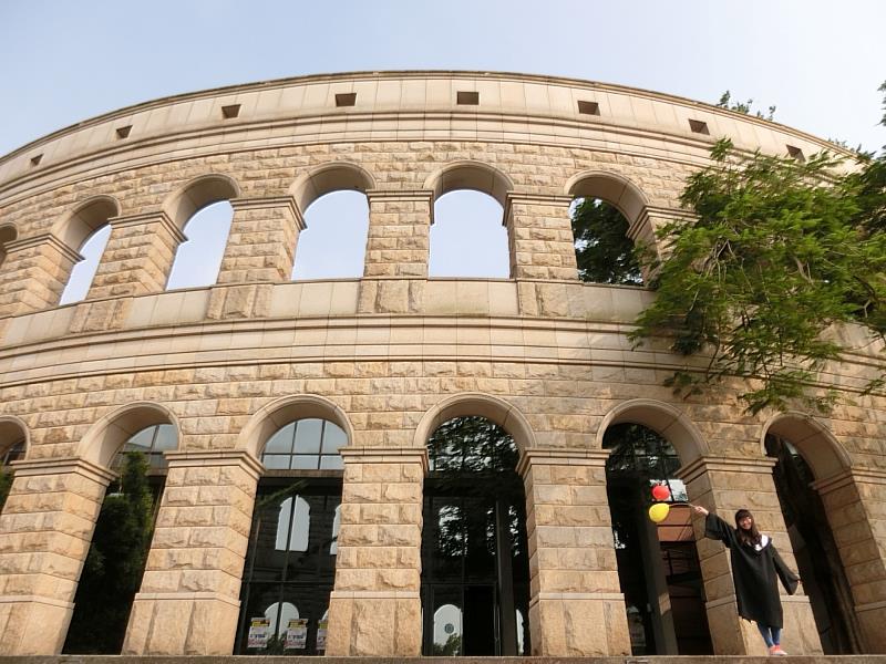 畢業生於體育館前，發揮創意拍下專屬的畢業紀念照。