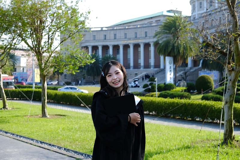 亞大學子穿上學士服，與典雅的行政大樓前開心留影，記錄青春。