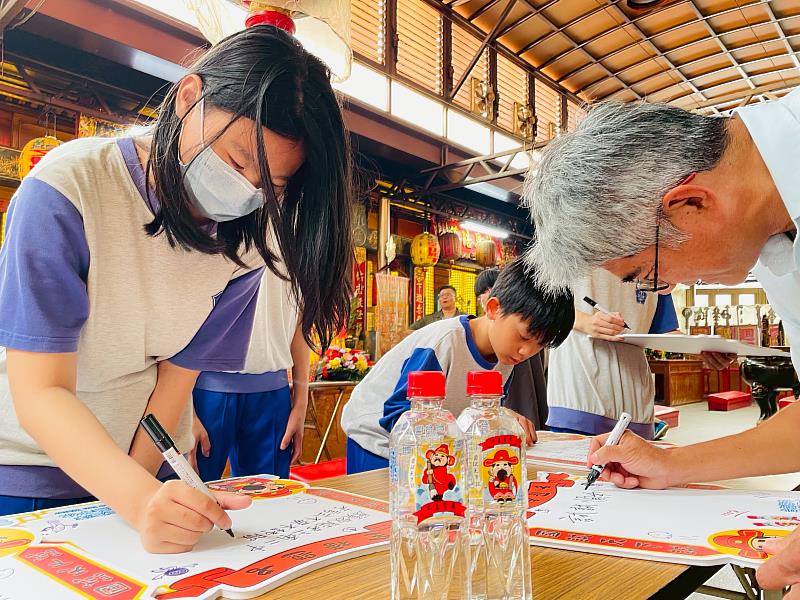 寫下夢想，全力以赴！成功國中校長鄭文鵬（右）帶領學生在祈福板寫下志願，搭配「台塩金榜題名水」的好運集氣，期許順利錄取理想學府。