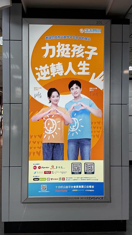 台北車站公益燈箱以亮橘色視覺呈現,藝人是元介與高伊玲擔任普仁青年關懷基金會代言人,透過「力挺孩子,逆轉人生」傳遞弱勢近貧學子支持理念,為謝卓燁推動的城市公益燈箱計畫注入關注度。(台灣摩菲爾提供)