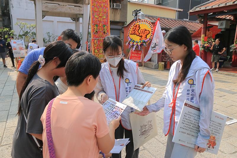 南臺科大USR團隊成員正引導參與民眾挑戰「街角康樂」實境解謎，透過互動圖卡與解謎提示，深入認識西羅殿獨特的「二十四節氣門神」，讓在地廟宇文化在遊戲互動中生動傳承。