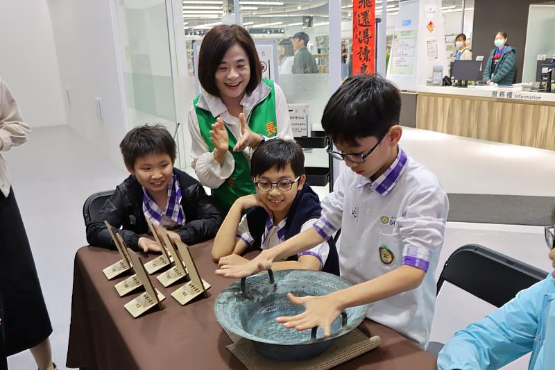 張榮發基金會執行長鍾德美（中著綠背心）與慈文國小學生一起進行龍洗盆水波紋實驗。