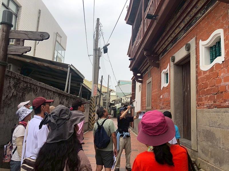 在八角樓斑駁的紅磚後巷，圖繪作家家永實引領學員深度解析後方鮮為人知的建築細部與傳統工法。學員們皆專注抬頭，一窺歷史建築的另一面。