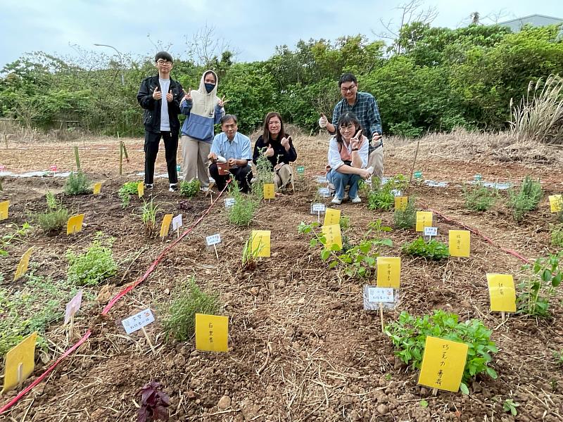 教務處同仁在排列整齊、標示清晰的新種植區旁合影，展示團隊合作成果。