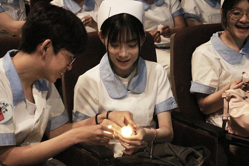 學生相互傳遞象徵生生不息的薪火蠟燭。