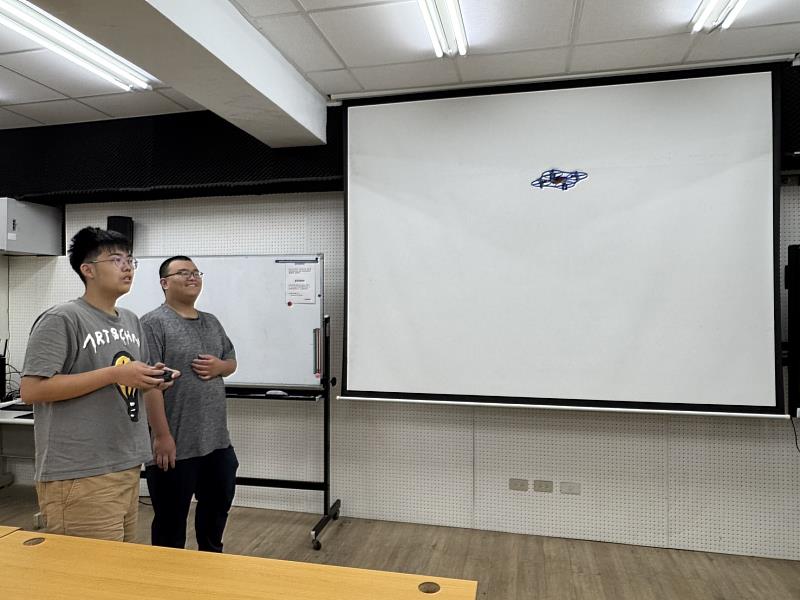 李奕翰（右）專題生示範3D列印自製無人機操作，並指導陳冠閔（左）進行操控。