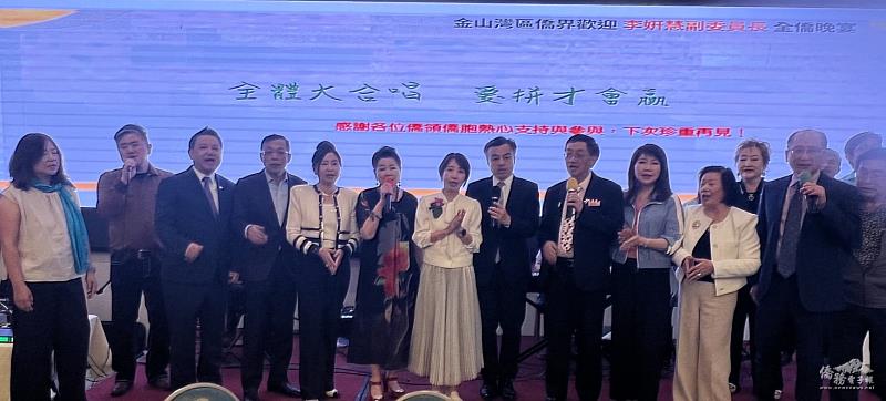 李姸慧（中）與僑領齊聲高唱〈愛拚才會贏〉。