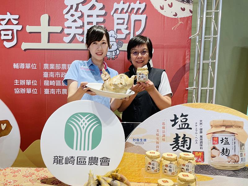 龍崎區農會總幹事林韋如（左）與臺鹽品牌行銷處長陳美文（右）展示以臺鹽「鮮選我塩麴」醃製料理的龍崎跑山土雞，共同推廣在地農產。