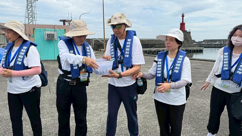 大家將魚苗置於水桶中，精準掌握時間、角度與力道接力傳遞，讓魚苗平安回歸大海。（靈鷲山佛教教團提供）