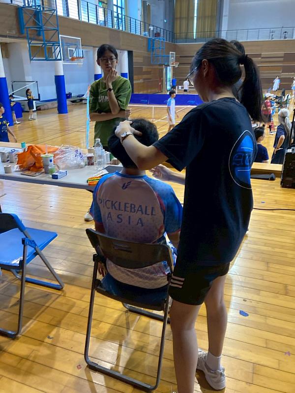 亞大物治系志工學生於場邊防護站，專注為參賽選手進行運動傷害評估。