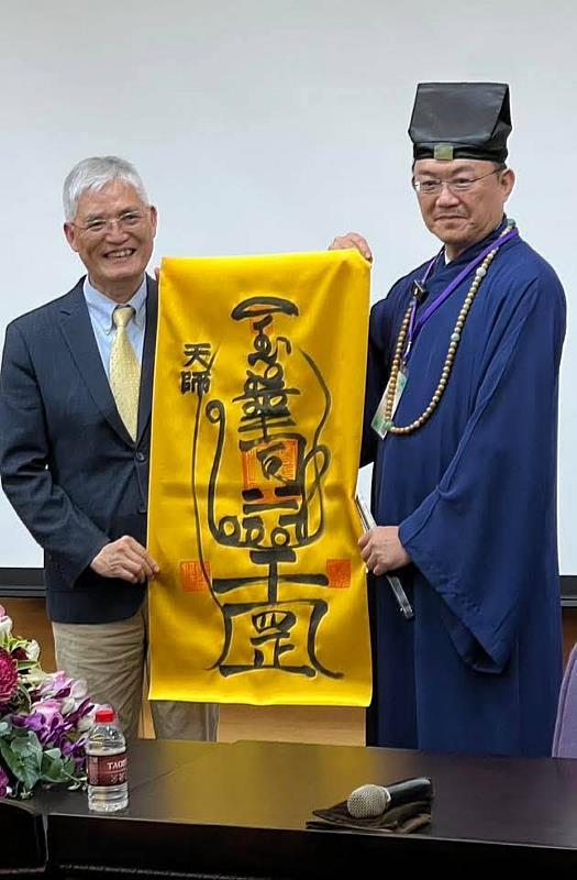 南華大學舉辦寺廟文化與管理論壇，張意將天師（右）致贈玉華司鎮宅符給高俊雄校長（左）。