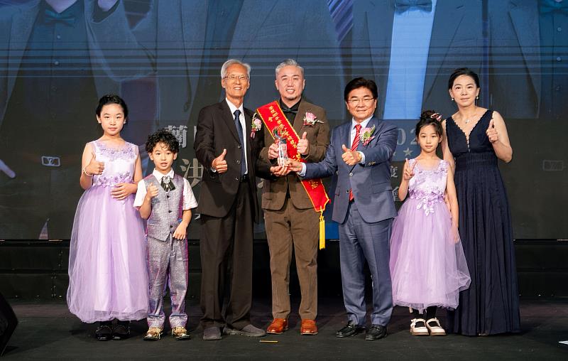蘭陽三區部洪昆憲業務副總經理(中)與家人一同上台接受總裁梁家駒(左3)以及廖學茂董事長(右3)頒獎。