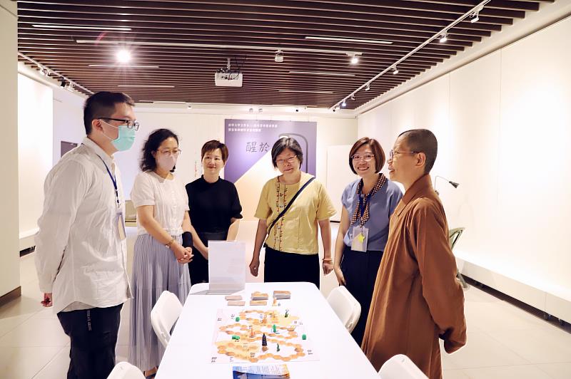 南華大學文學系舉辦「醒於微光」畢業成果展，學生向師長介紹「敦煌探險隊」桌遊作品。