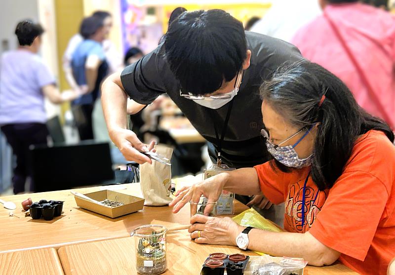 青年夥伴耐心協助長輩完成植栽作品，在互動過程中展現跨世代互助與交流精神。