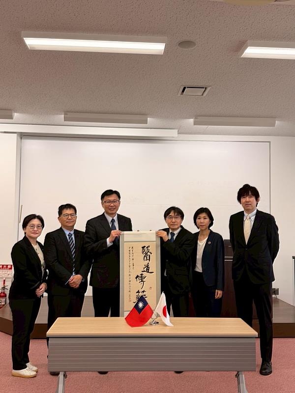 顏宏融院長致贈墨寶「醫道傳薪」，日方由加藤真介學部長代表接受，期勉雙方共同傳承與創新傳統醫藥。