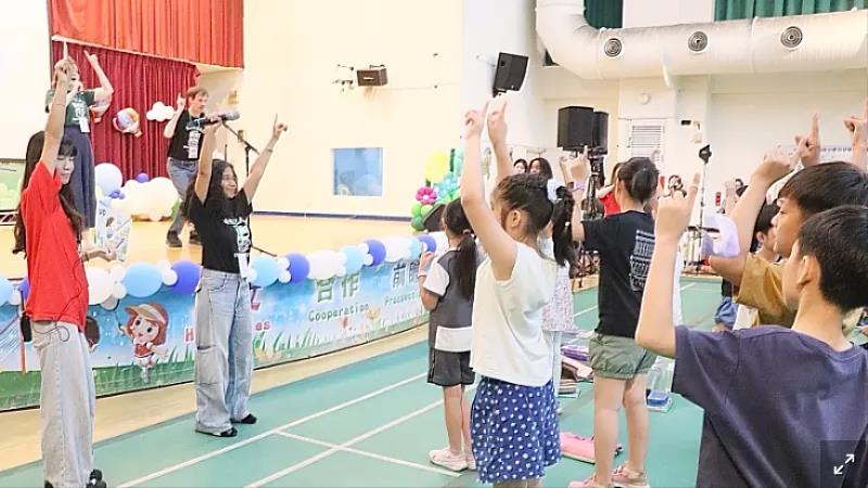 外籍學生於舞台前帶領學童進行互動式國際文化活動，透過肢體律動與趣味教學，讓孩子在歡樂氣氛中學習外語與多元文化。