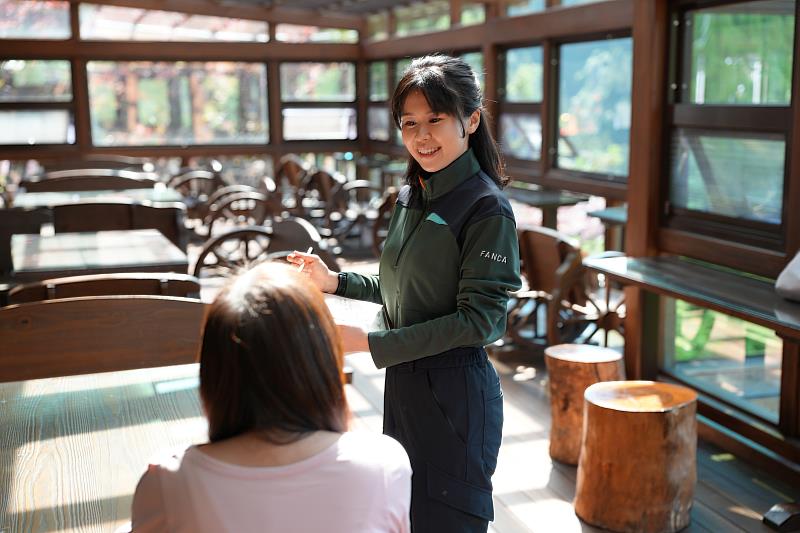 森林遊樂區服務人員向遊客介紹餐點。