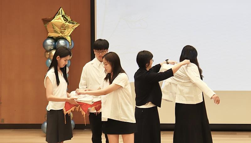 師長為學生披上短白袍，代表學生從公共衛生專業學習者，邁向準公共衛生師的重要身分轉換。