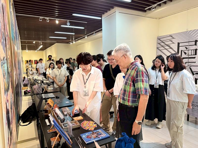 南華大學視設系《層影》畢業展，展現創意能量與設計實力，學生向師長介紹作品。