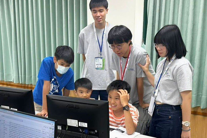 NYCU student volunteers mentor elementary school students during a BeLight AI Semiconductor workshop, guiding them through hands-on activities that introduce programming, AI, and semiconductor concepts in an engaging and accessible way.