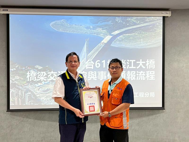 新北市政府消防局局長陳崇岳（左1）代表致贈感謝狀予交通部公路局北區養護工程分局主任工程司楊秉順（右1），感謝該分局協助辦理淡江大橋橋梁管理中心參訪交流事宜。