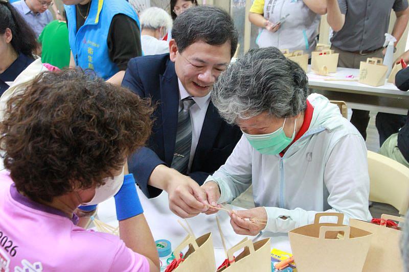 元培王綮慷校長(中)於手作互動「巧手竹編船」中,與長輩一同完成竹編船。