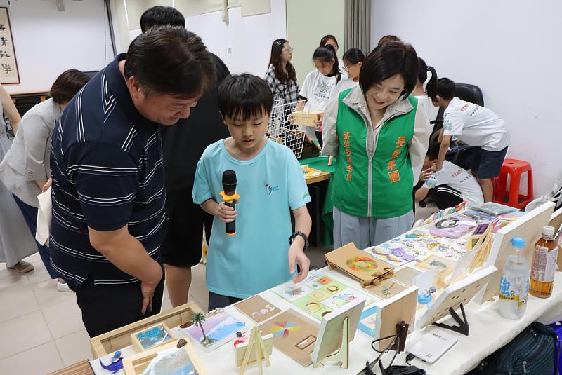 張榮發基金會執行長鍾德美(右一)與基隆市教育處課程教學科課程督學巫建男(左一)聆聽長樂國小學生說明創客作品設計過程。