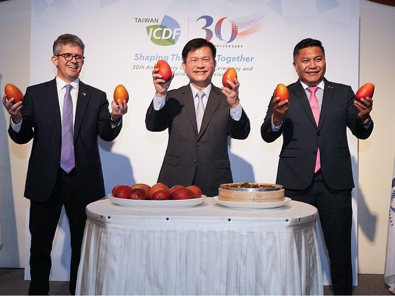 Minister Lin Chia-lung, flanked by Minister Joaquín Barnoya on the left and Minister Kalani Kaneko on the right, holds up sweet Taiwanese mangoes for a group photo.