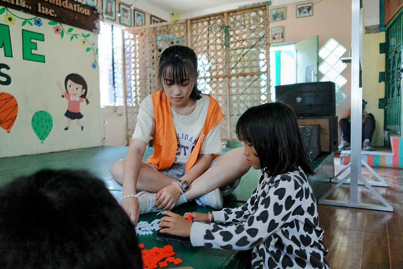 邱琬寧在機構內指導孩童遊玩桌遊,在遊戲交流中培養孩子的邏輯思考,現場充滿溫馨的氛圍。