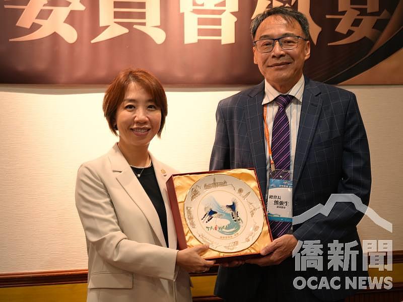 李姸慧（左）代表僑委會致贈臺灣藍鵲彩繪瓷盤予世界臺灣商會聯合總會總會長熊強生（右）。