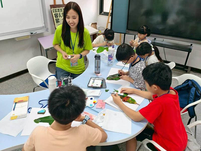 營隊中,志工與學生一起在小石頭及落葉上作畫。