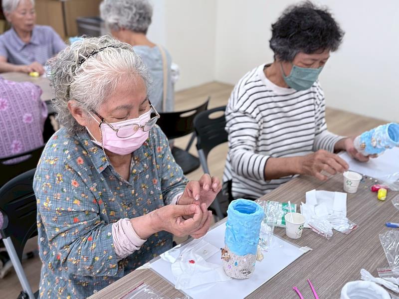 長輩們正在專心將貝殼與珍珠裝飾於花瓶。