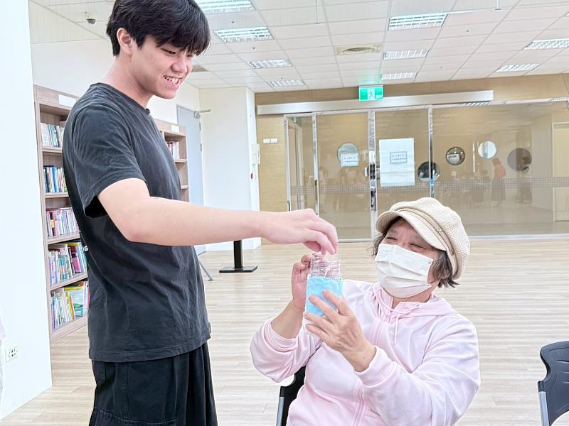 長輩與大學生交流自己製作的花瓶構想。