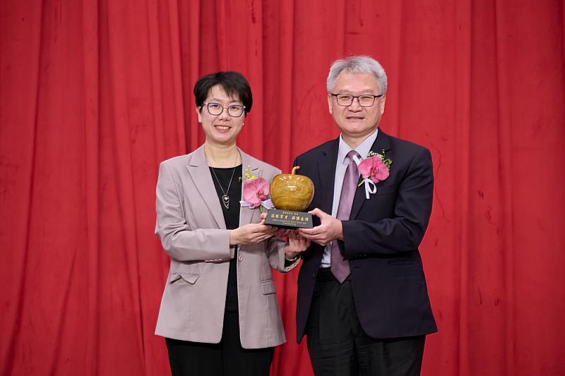 財團法人中山醫學大學董事長周英香(左)致贈校園桃花心木雕製的蘋果紀念藝品予卸任校長黃建寧,感謝其深耕教育、培育人才,為中山醫大奠定穩固發展基礎。