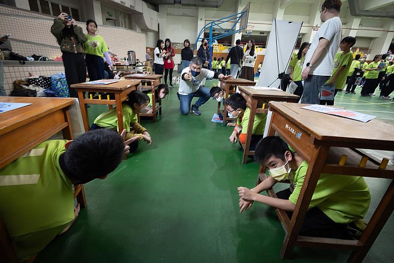 孩子在課桌椅下感受籠飼母雞的擁擠生活,進而產生同理心。