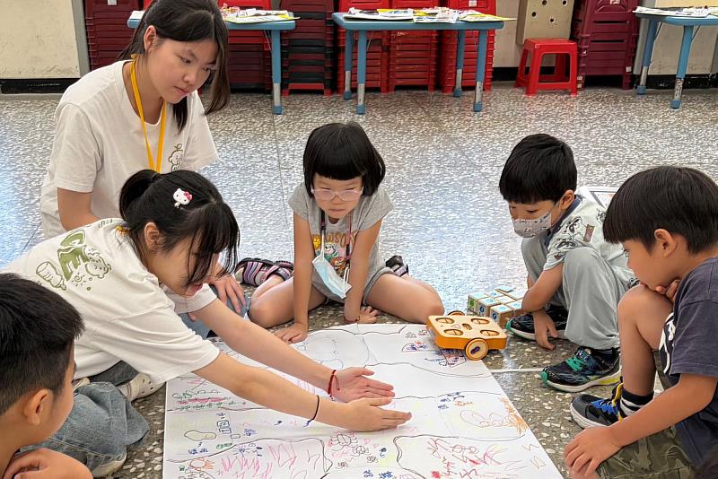 南大師資生陪伴幼兒運用程式指令挑戰自創KIBO機器車關卡,在合作探索中提升科技素養與創新思維。