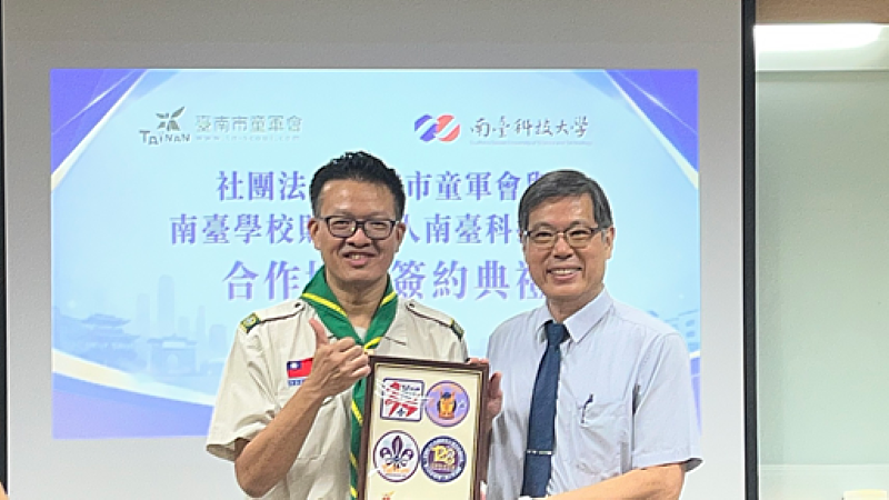 臺南市童軍會理事長楊智雄(左)與南臺科大副校長王振乾(右)於會中交換紀念品並開心合影。