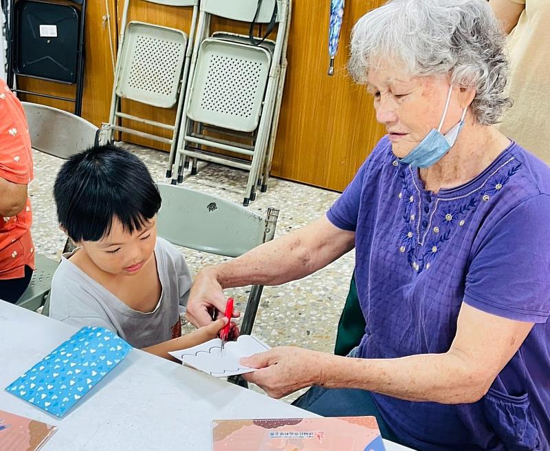 社區長輩細心協助幼童使用剪刀製作圖樣,體現社區「老少共融」與互助共學的意涵。