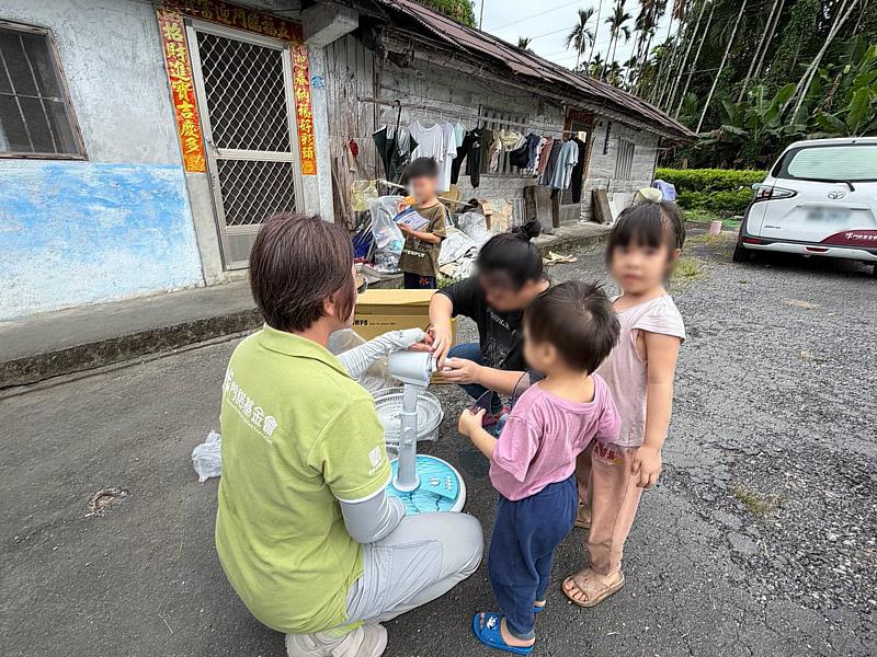 門諾基金會早療團隊與楊氏姊弟倆、媽媽一起在屋外組裝新電風扇，孩子們也開心參與。
