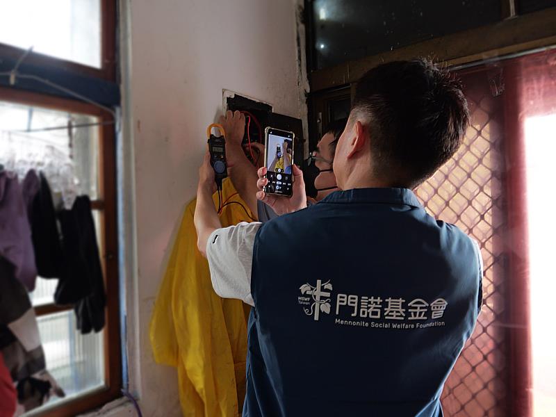 門諾基金會同仁與沃克工程行水電師傅使用數位勾表，檢查案家配電箱（總開關）電流狀況，掌握居家用電安全。