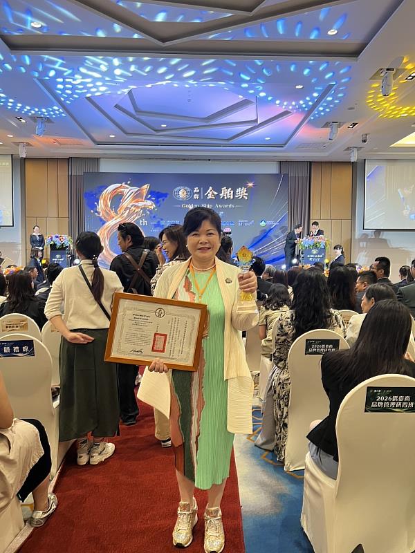 林妙娟董事長展示第8屆品牌金舶獎獎座及獲獎證書。