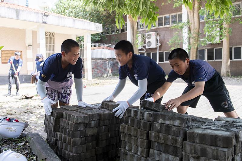 關西國中少棒隊球員加入修繕行列，針對地面平整工程，逐一移除連鎖磚磚體
