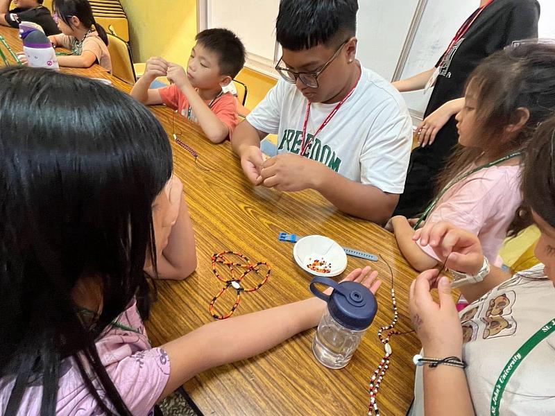 孩子們圍坐在桌前,互相交流串珠技巧,體驗動手做的樂趣。