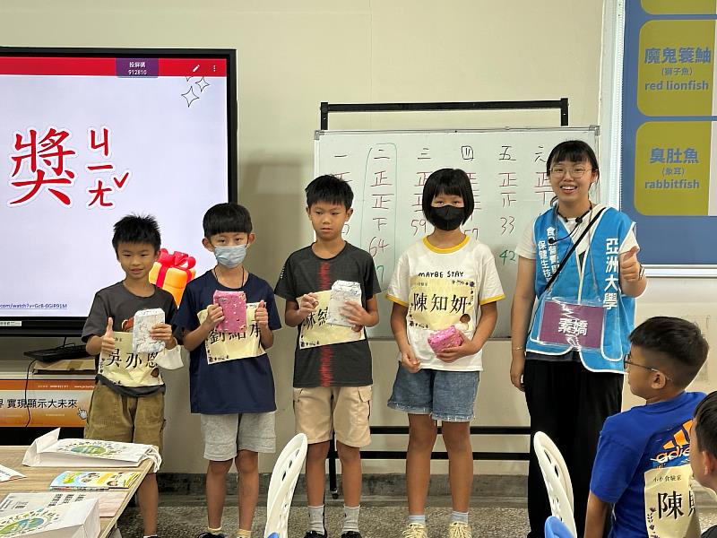 亞大學生顏語彤(右1)頒發破冰活動競賽獎品予獲勝小學員,並合影留念以茲鼓勵。