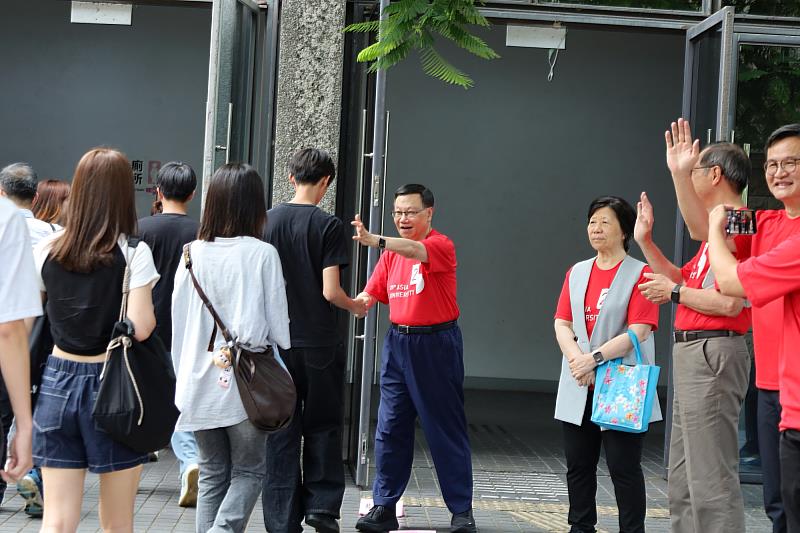 校長與主管在體育館入口親切迎接新生，以握手、揮手歡迎新鮮人報到。
