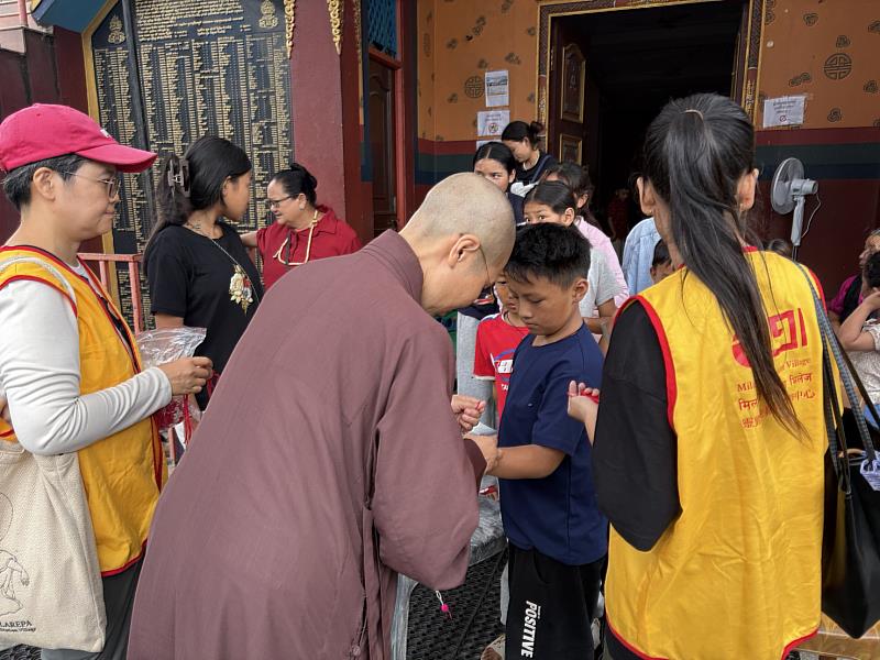 密勒日巴禪修中心法師為災民綁上五佛珠紅線,祝福平安。(圖由靈鷲山佛教教團提供)